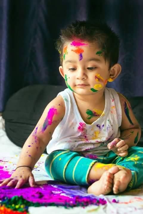 a little boy that is sitting on the ground with some paint all over his face