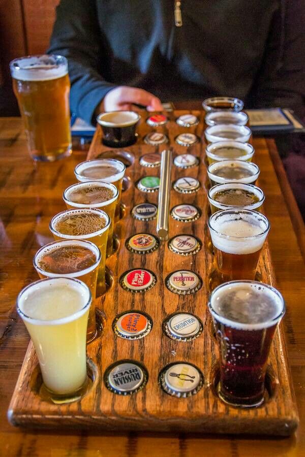 a wooden tray filled with lots of different types of beer glasses on top of a table