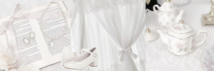 there is a white wedding dress and shoes on the table next to an open book