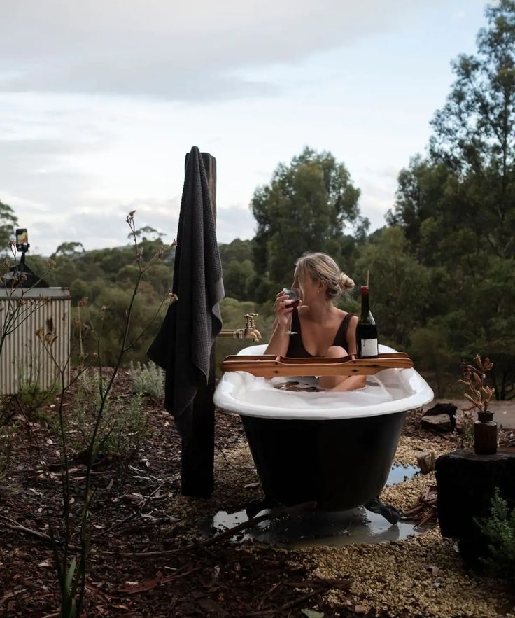 a woman sitting in a bathtub drinking wine