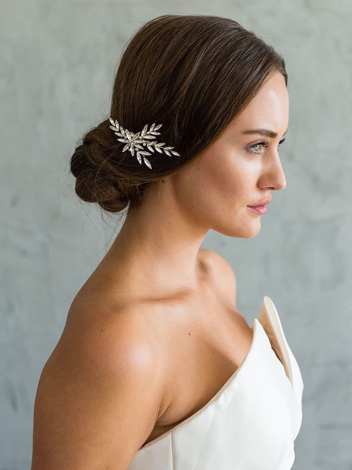 a woman in a white dress wearing a bridal hair comb with flowers on it