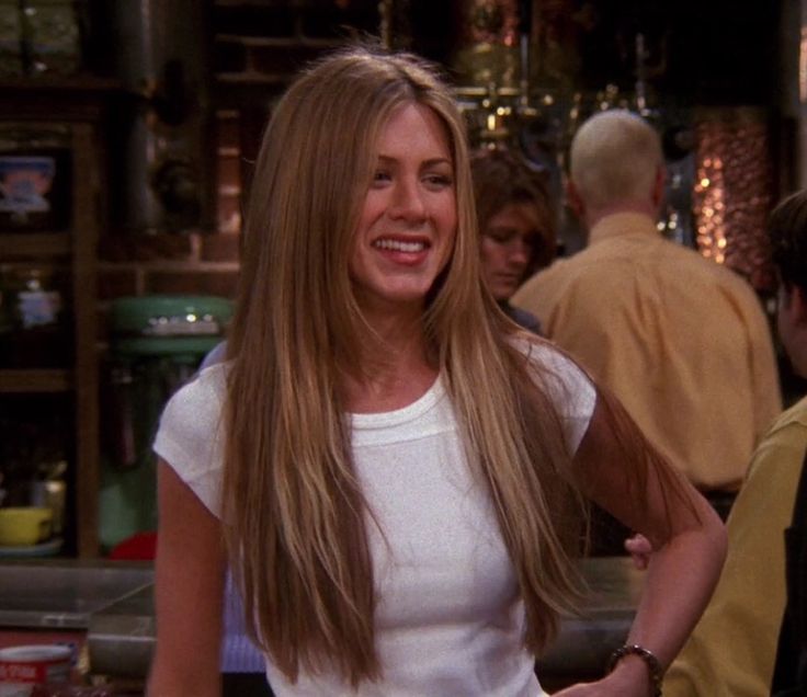 a woman with long hair standing in front of a bar and smiling at the camera