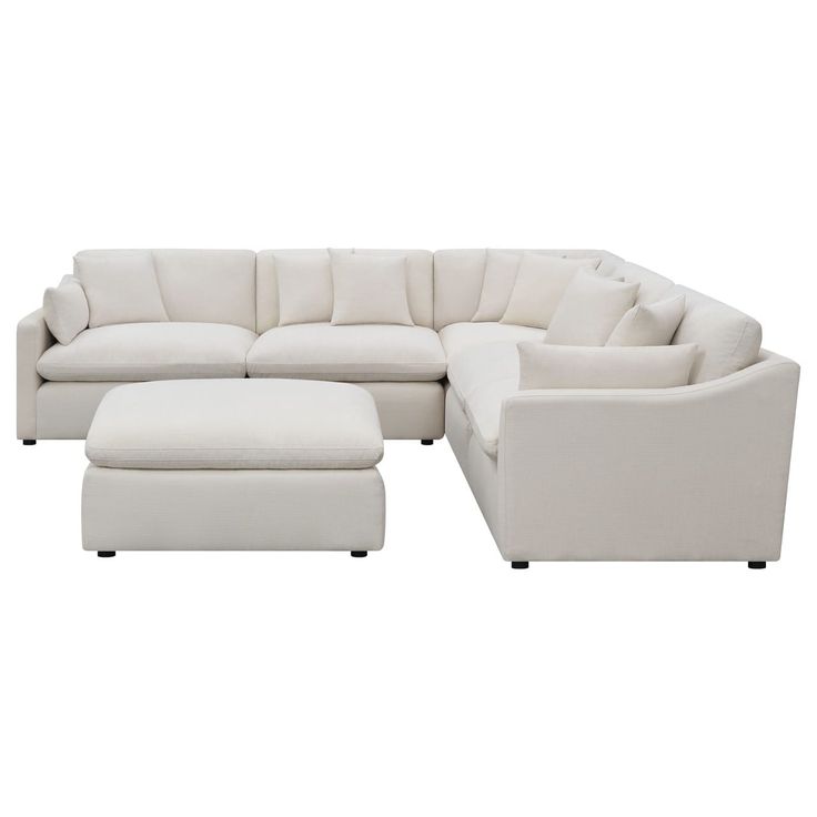 a white sectional couch with ottoman and footstool in front of a white background