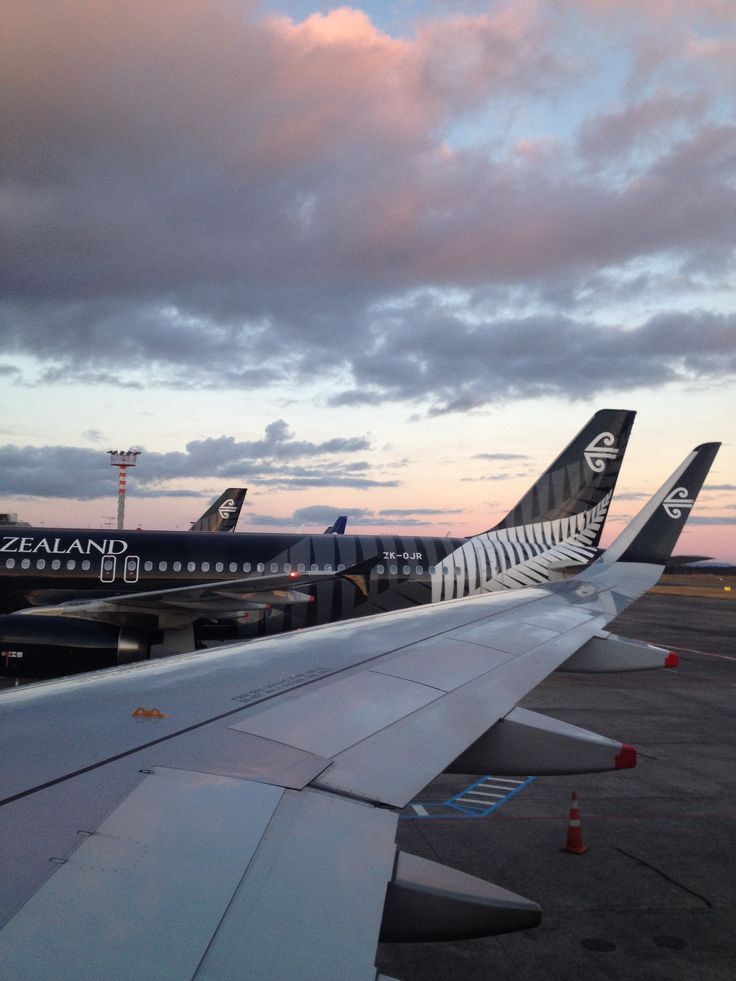 the wing of an airplane as it sits on the tarmac with other planes in the background