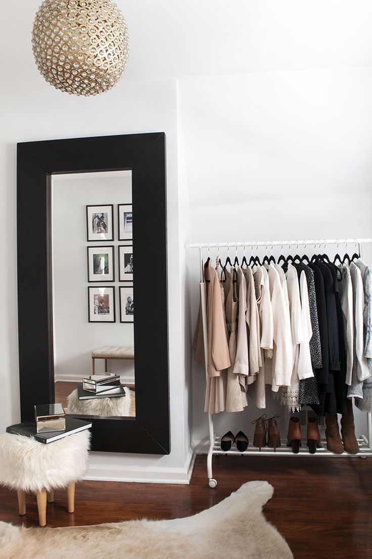 a room with a mirror, coat rack and sheepskin rug in front of it