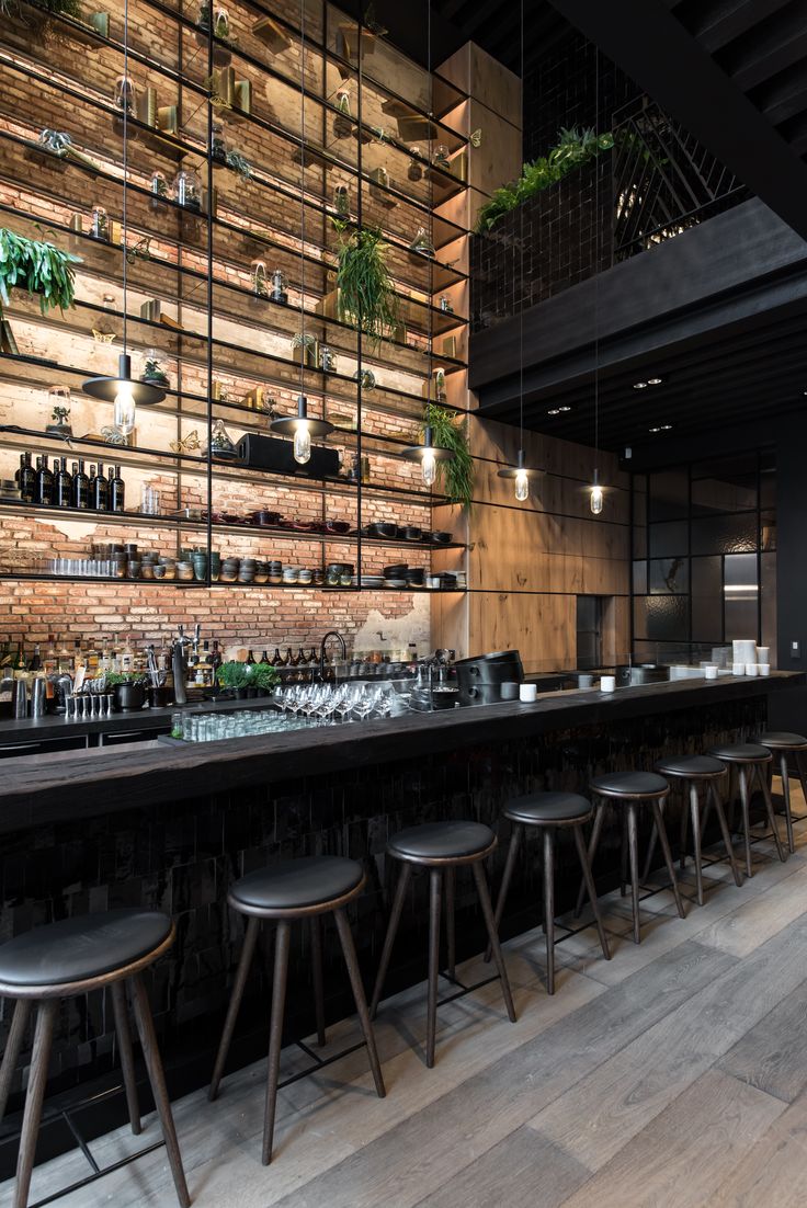 an empty bar with stools and shelves full of bottles on the wall behind it