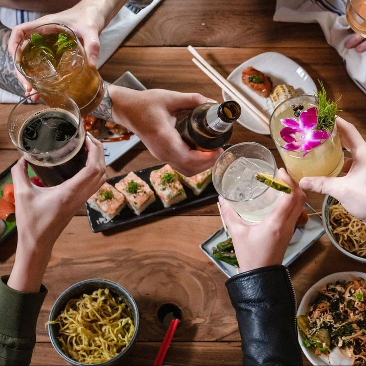 several people toasting at a table with food and drinks