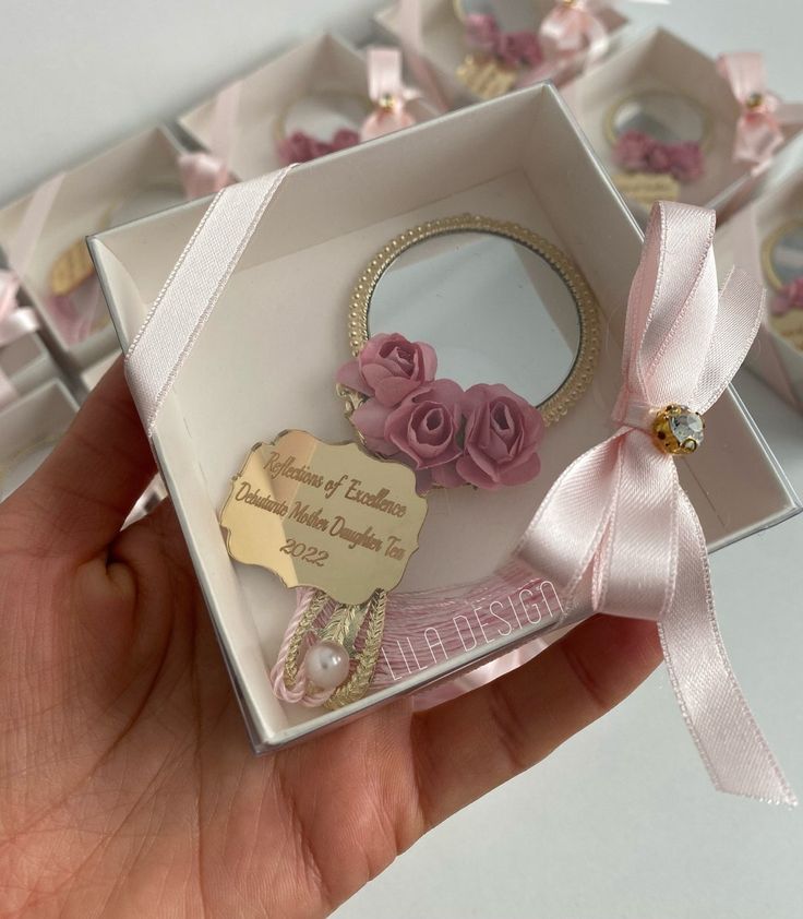 a hand holding a small white box with pink flowers on it and a tag that says, i love you