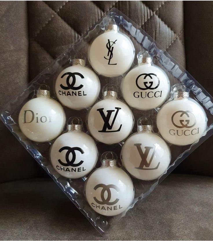 a bunch of ornaments that are sitting in a box on a couch with the words chanel written on them