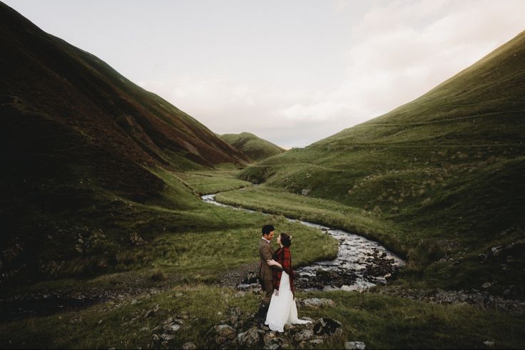 a bride and groom standing in the middle of a valley