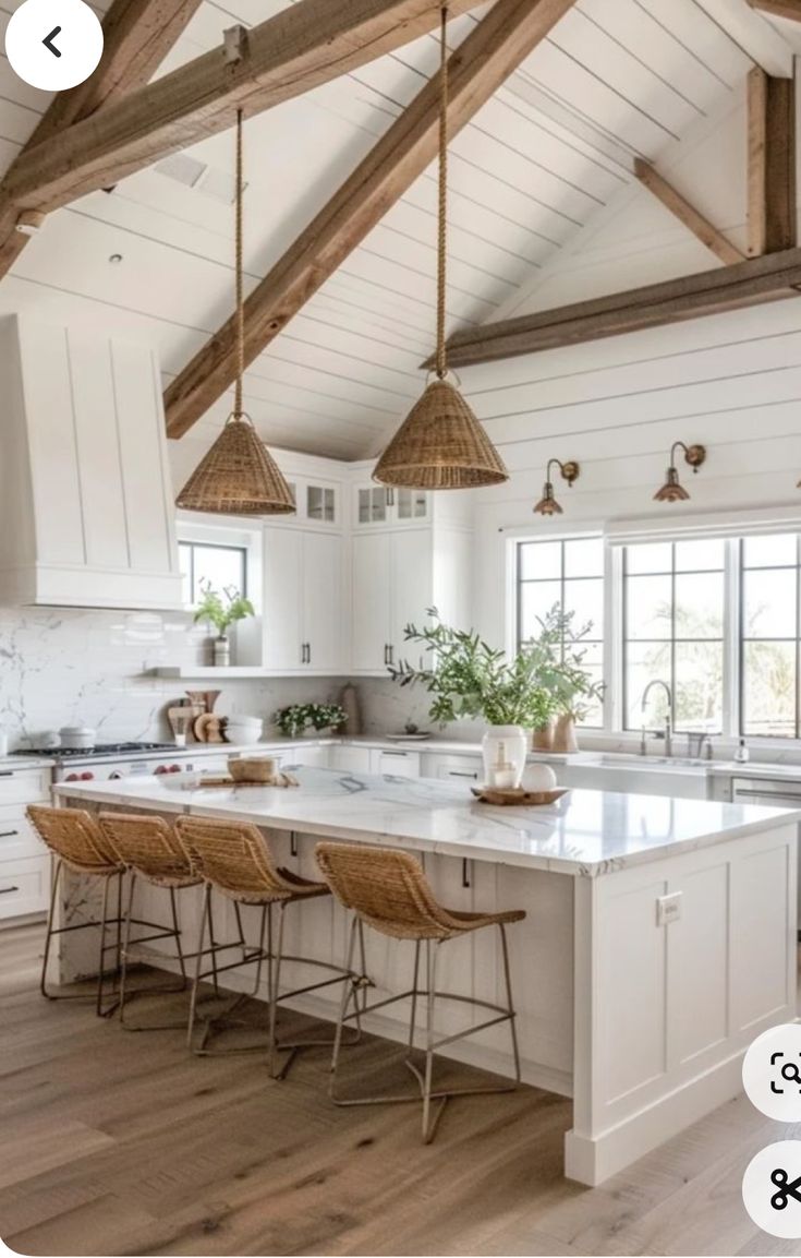 an open kitchen with white cabinets and wooden beams on the ceiling, along with wicker bar stools