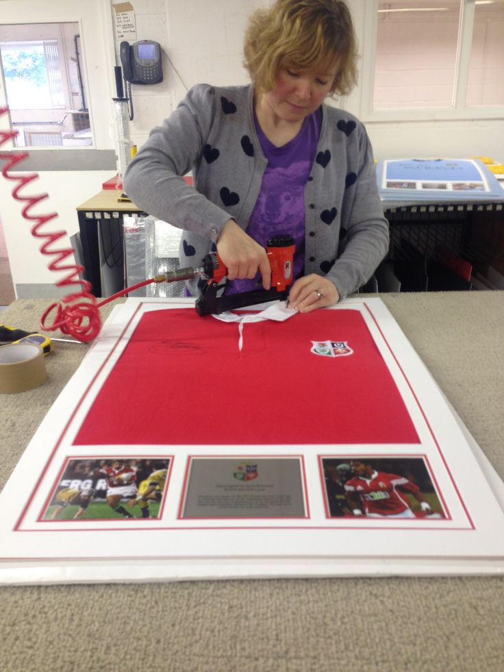 a woman is working on a large red and white framed artwork with pictures around it