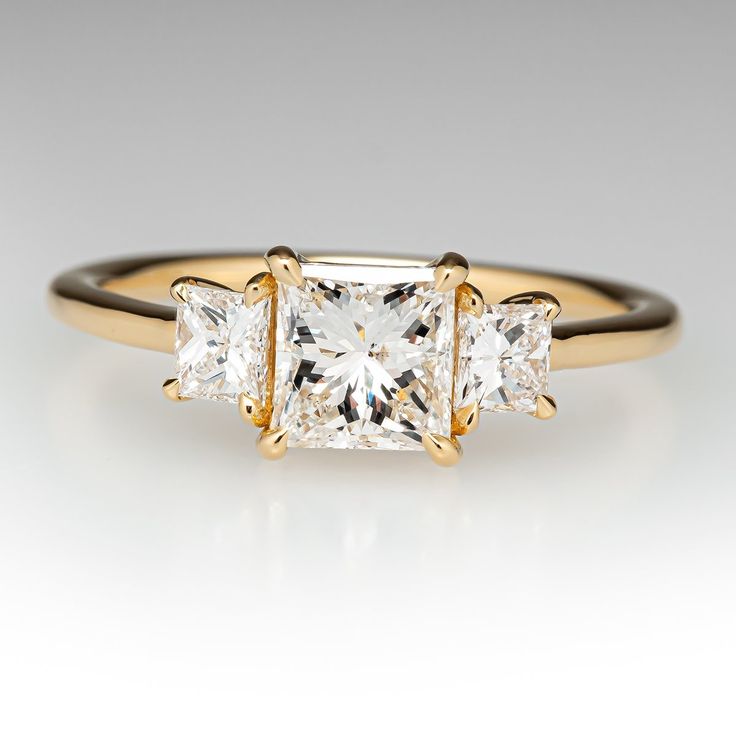 three stone engagement ring in yellow gold with princess cut diamonds on the sides and side stones