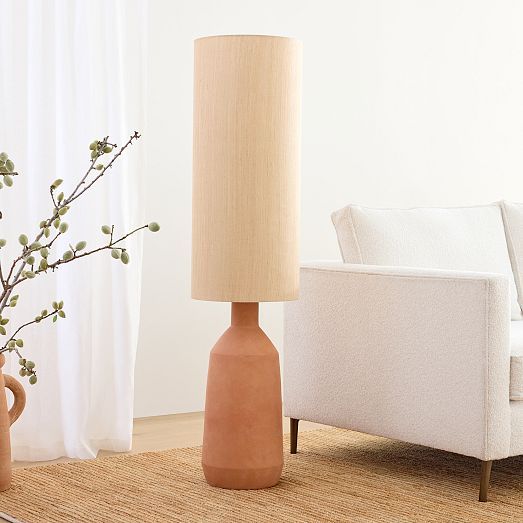 a table lamp sitting next to a couch in a living room with white walls and curtains