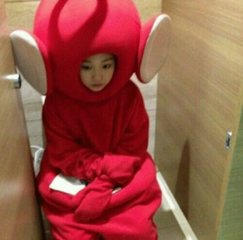 a young child in a red costume sitting on a toilet with its head covered by a towel