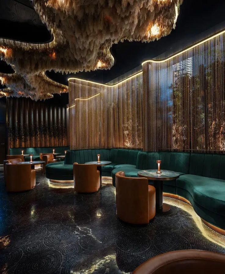 an elegant restaurant with green velvet booths and chandeliers hanging from the ceiling