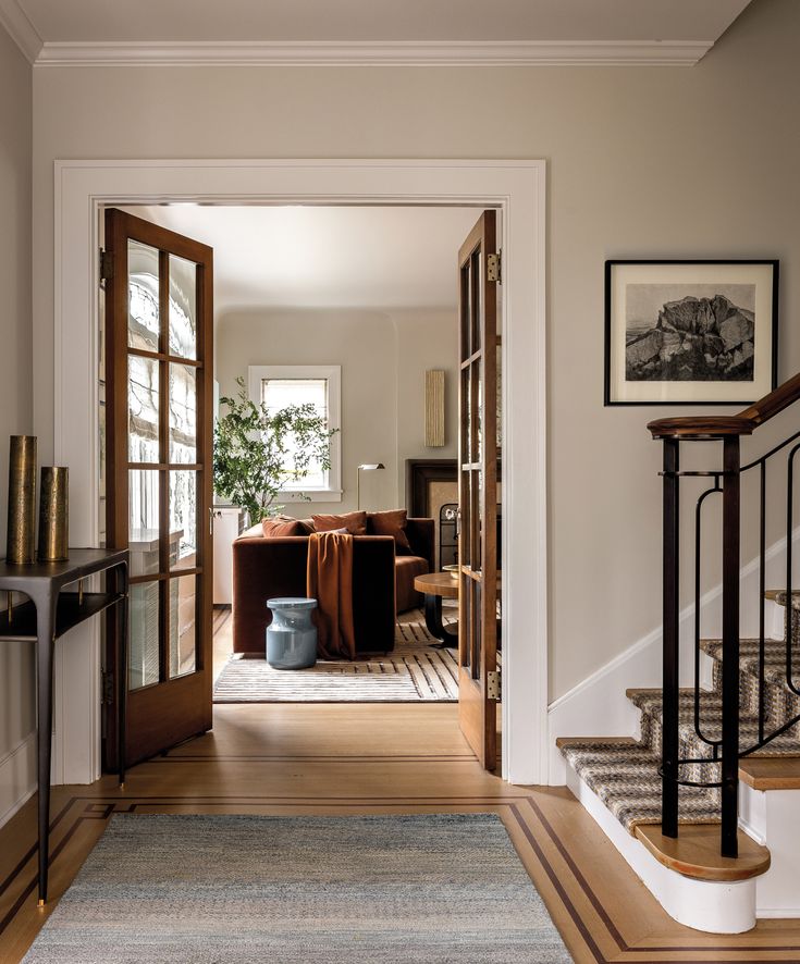 an entry way leading to a living room and dining room with wood floors, white walls, and wooden stairs