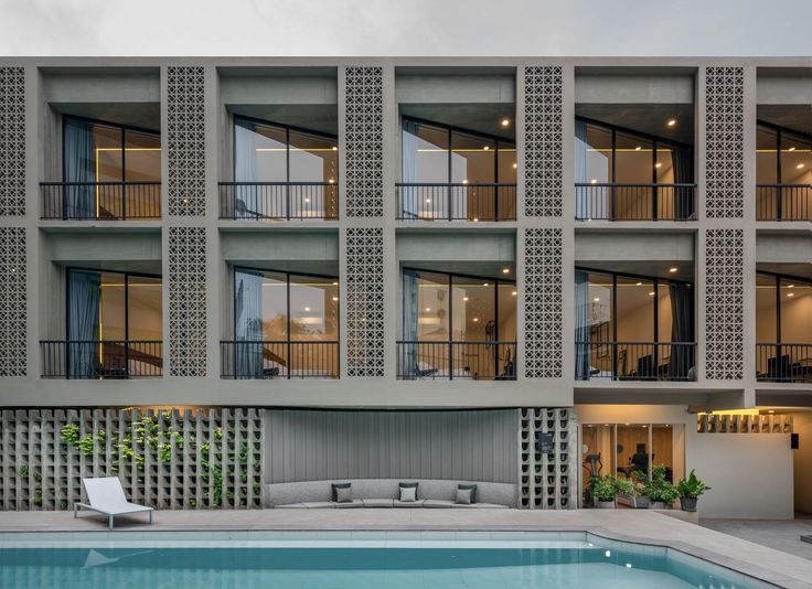 an apartment building with a swimming pool in the foreground and several balconies on the second floor