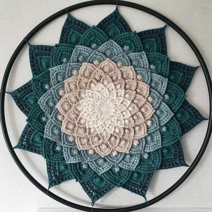 a circular crocheted wall hanging with a flower design on it's center