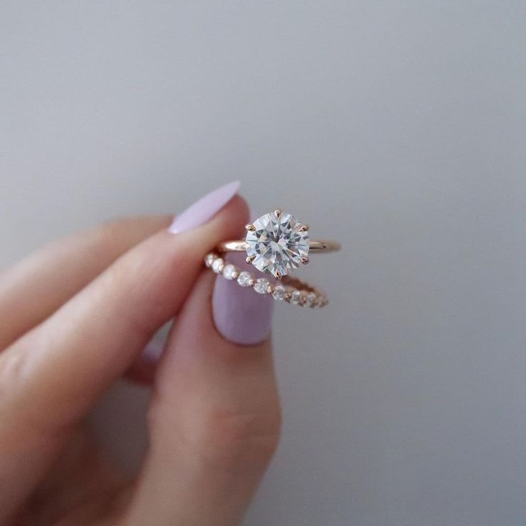 a woman's hand holding an engagement ring with two diamonds on the top and bottom