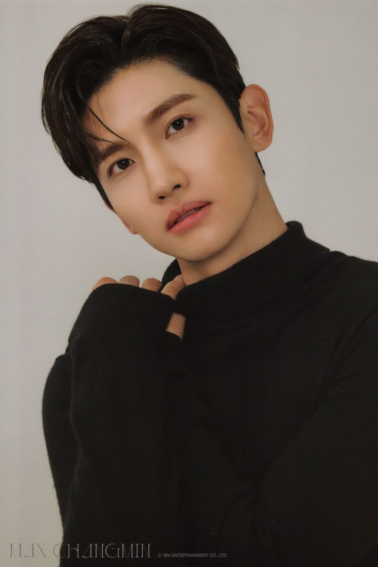 the young man is wearing a black turtle neck sweater and posing for a photo with his hands on his chest