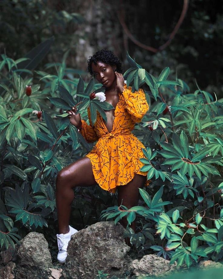 a woman in an orange dress is posing for the camera with her hand on her face