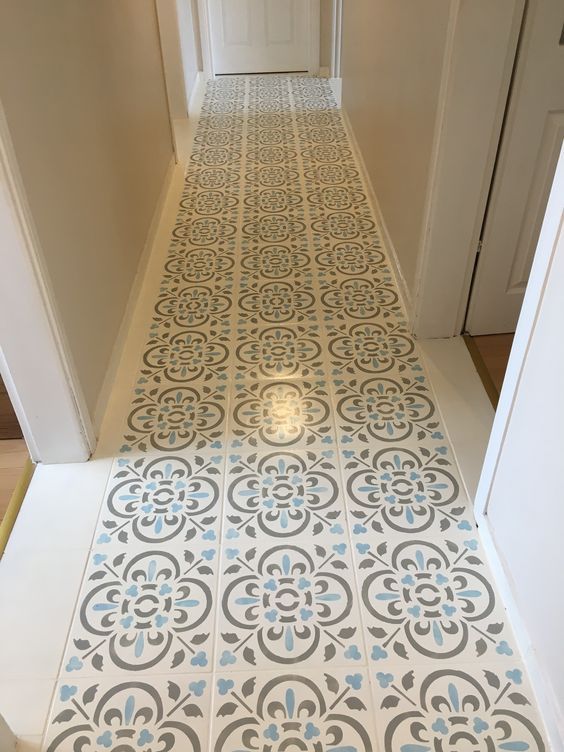 a hallway with an ornate tile floor and white door way leading to the entrance area