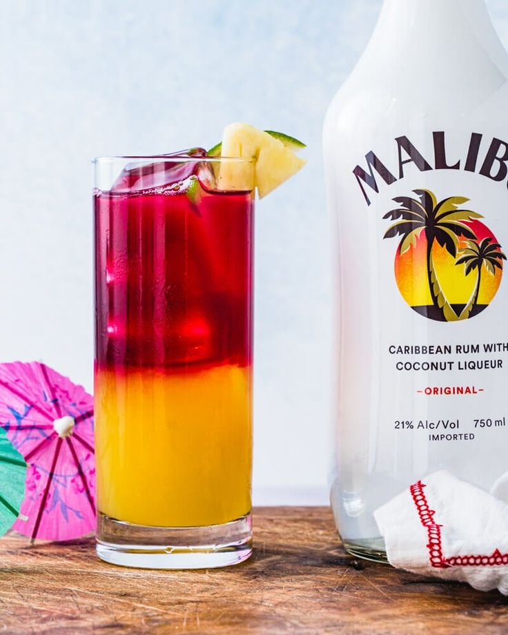 a colorful drink next to a bottle and umbrella