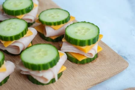 cucumber and cheese sandwiches are arranged on a cutting board