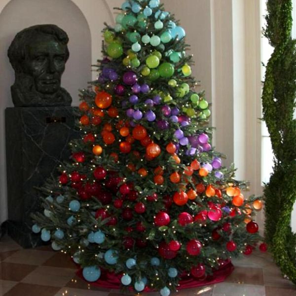 a decorated christmas tree in the middle of a room next to a busturine