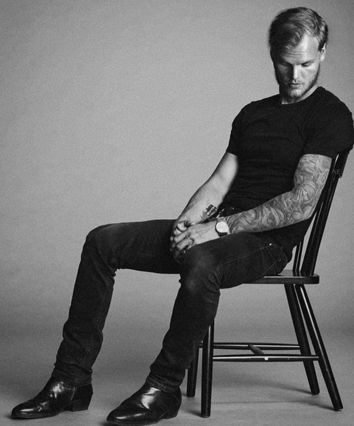 a man with tattoos sitting in a chair