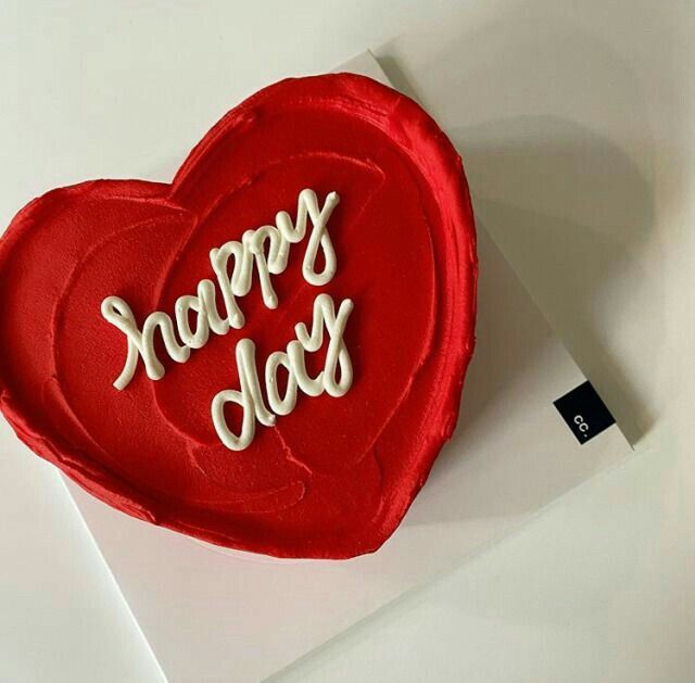 a red heart shaped cake sitting on top of a white table