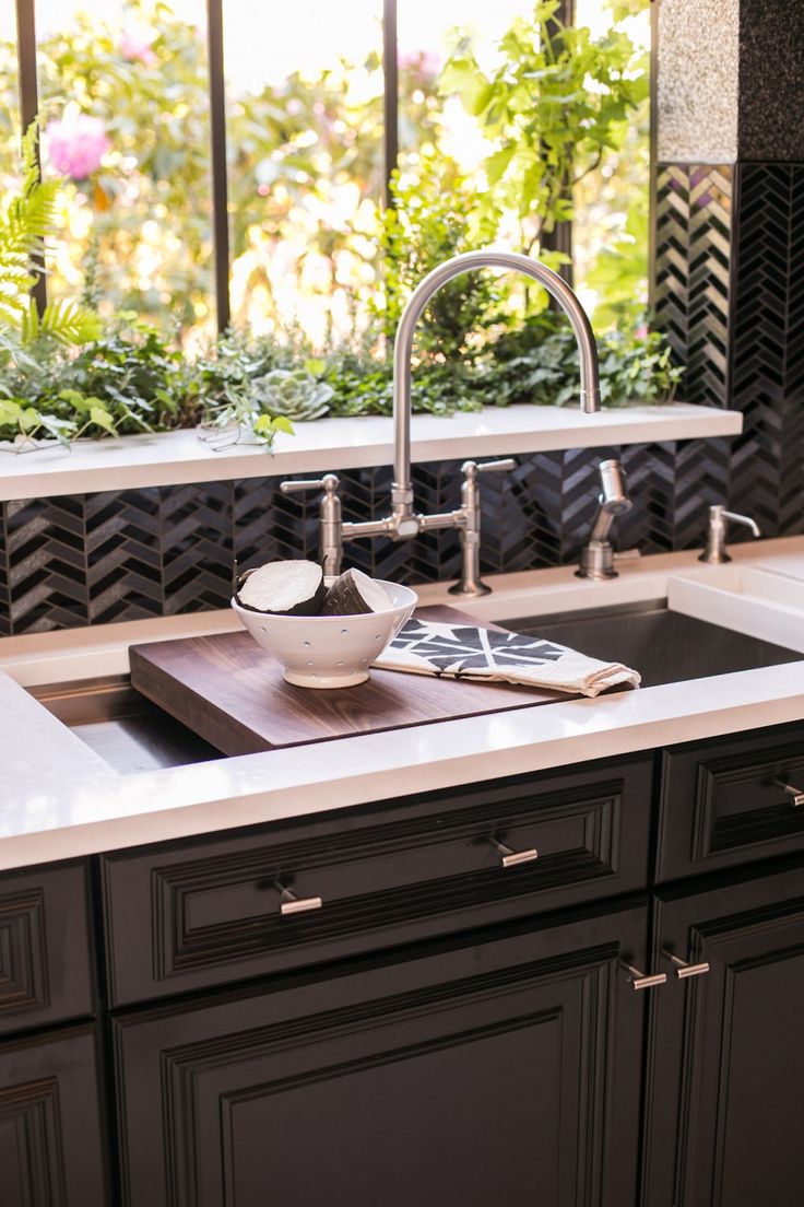 a kitchen sink sitting under a window next to a counter top with dishes on it