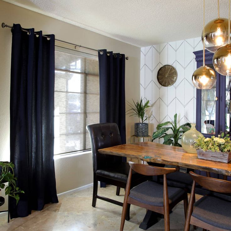 a dining room table and chairs with black curtains