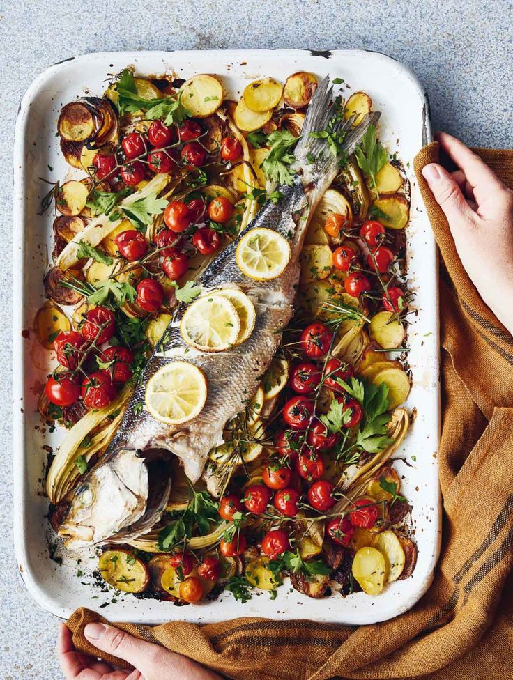 someone holding a platter with fish and vegetables on it