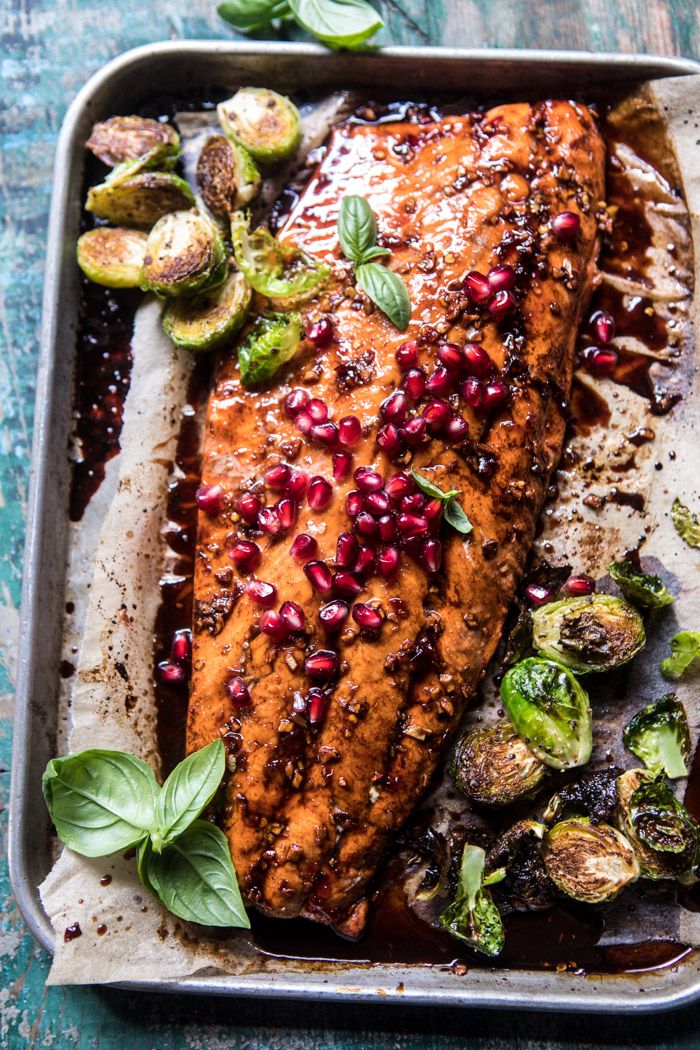 salmon with pomegranates and brussel sprouts on a baking sheet