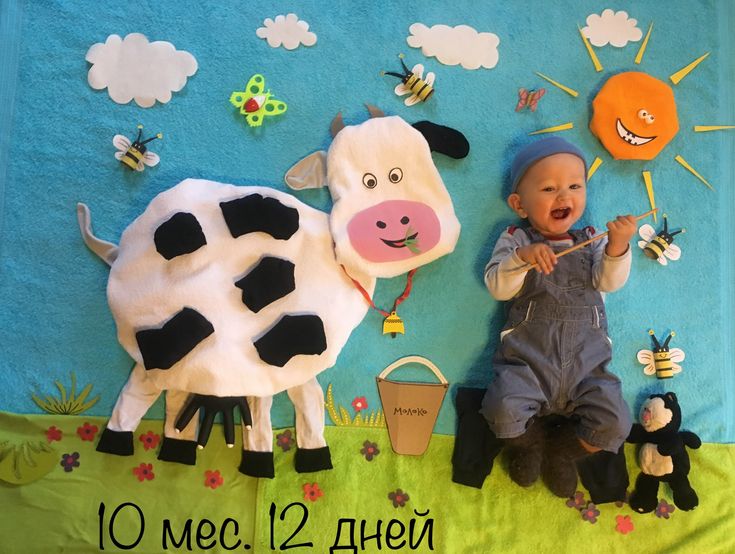 a baby is laying on the ground next to a cow and other farm related items