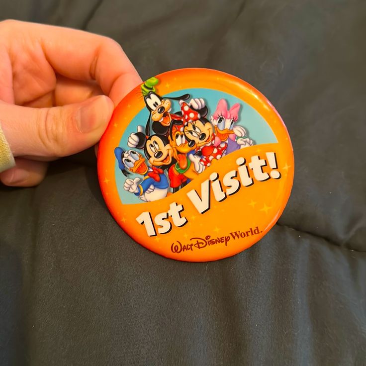 a person is holding an orange disney world badge