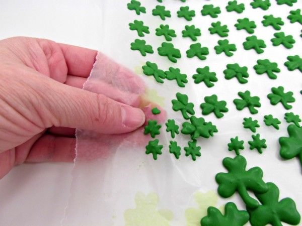 someone is cutting out green shamrocks on a sheet of white paper with their fingers