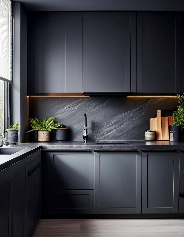 a kitchen with black cabinets and white counter tops is pictured in this image, there are potted plants on the window sill