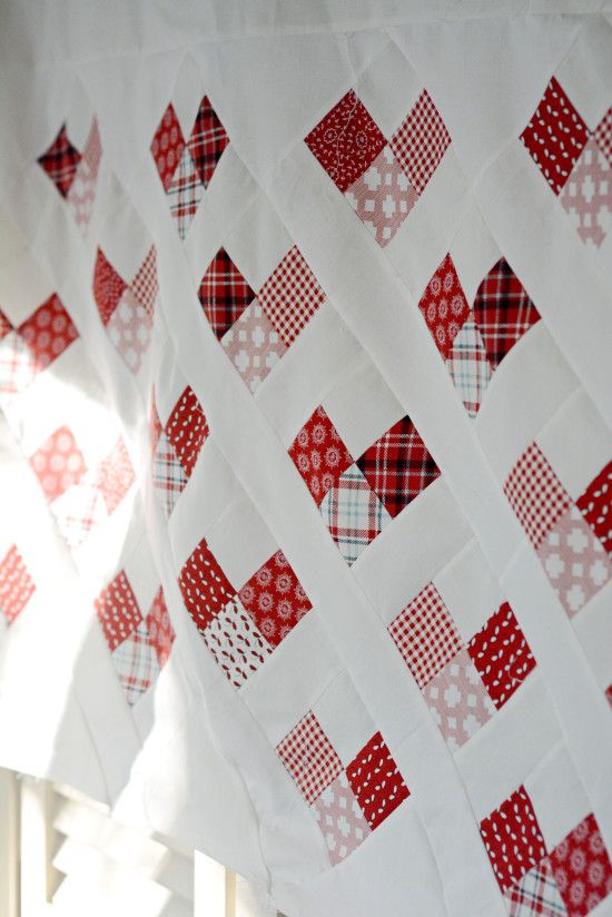 red and white patchwork quilt hanging from a window