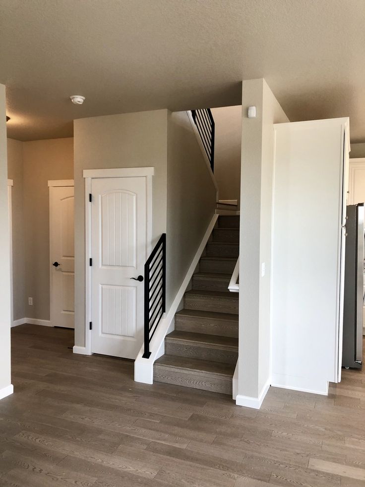 an empty living room with stairs leading up to the second floor and another open door