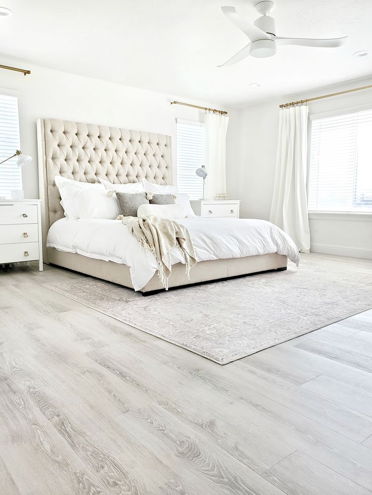 a bedroom with white furniture and wood floors