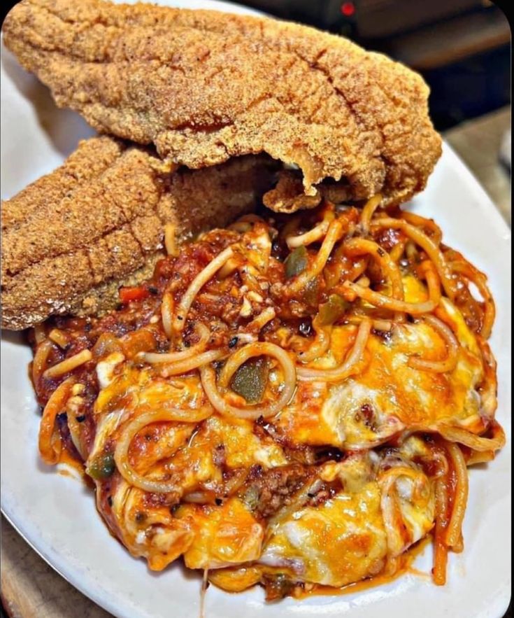 a white plate topped with spaghetti and fried chicken