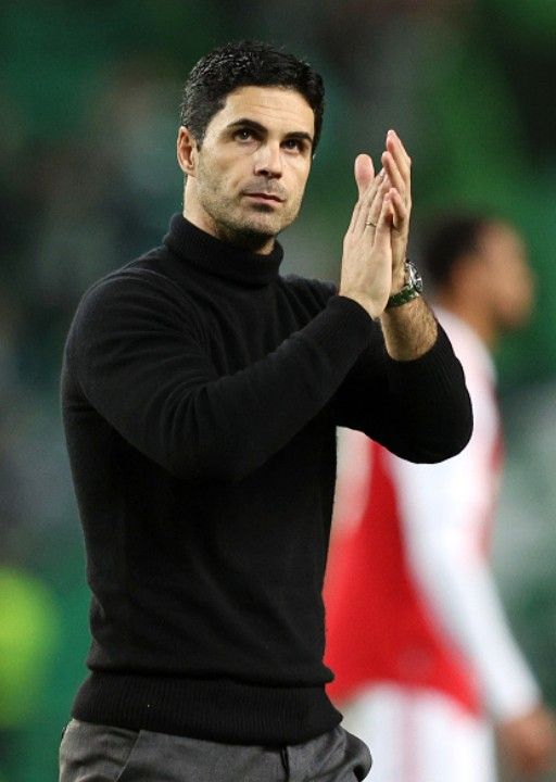 a man in black shirt and grey pants clapping with his hand up to the side