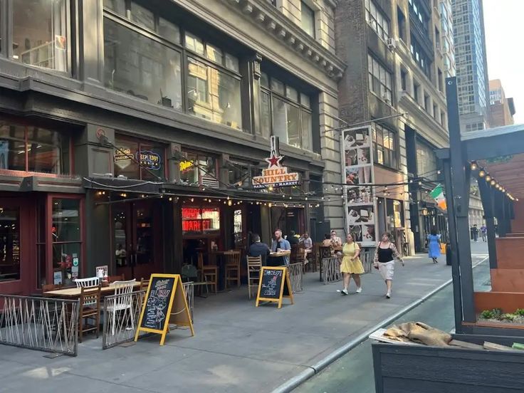 people walking down the sidewalk in front of a restaurant