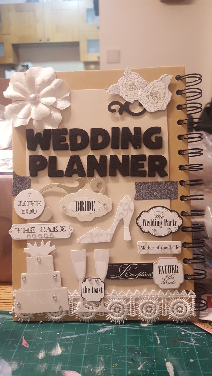 a wedding planner is displayed on a table with flowers and laces around it's edges