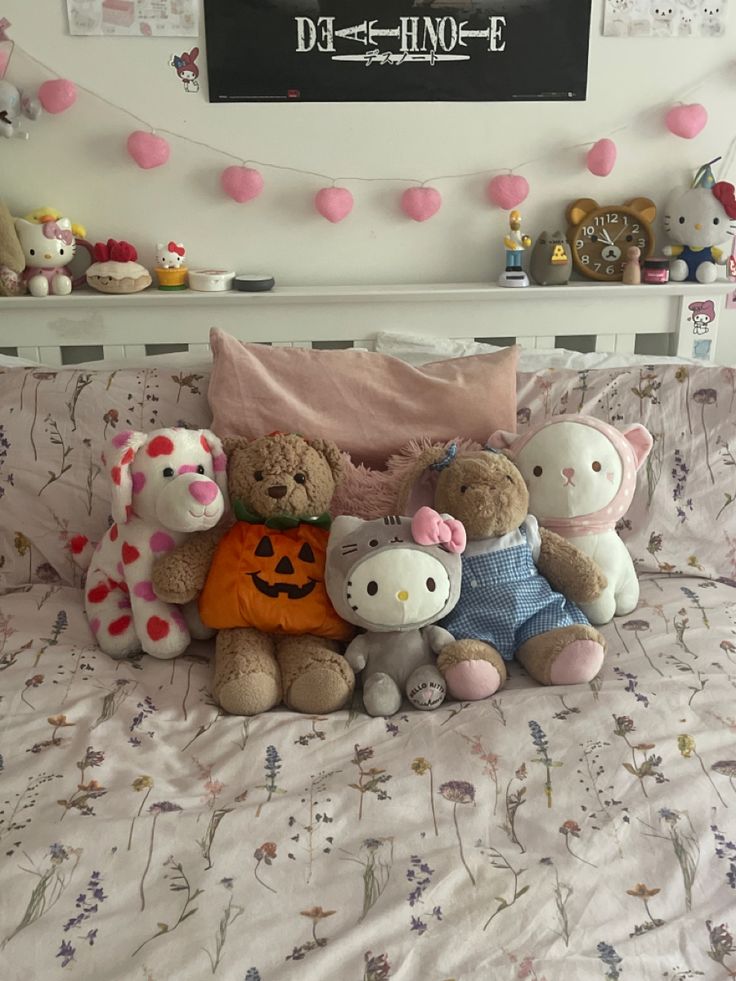 there are many stuffed animals sitting on the bed with pink and white decorations above them