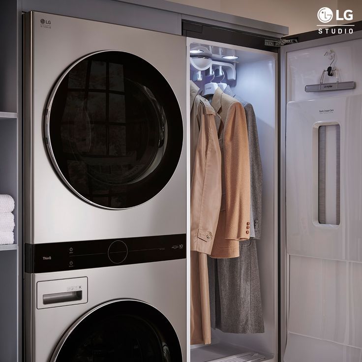 a washer and dryer in a room with clothes hanging on the rack next to each other