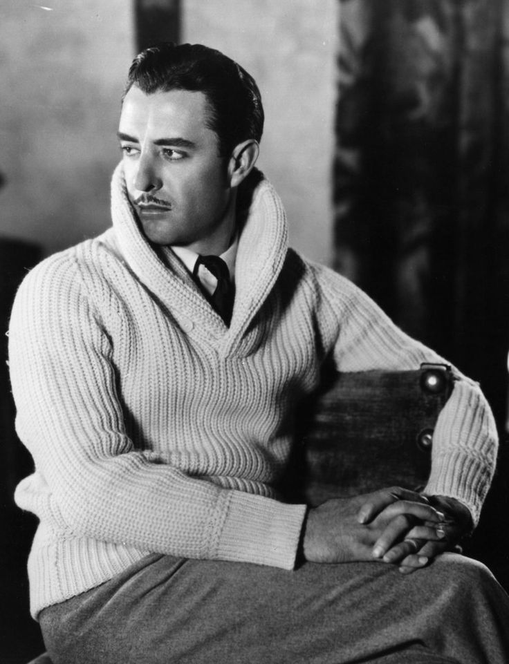 a man sitting in a chair wearing a sweater and tie